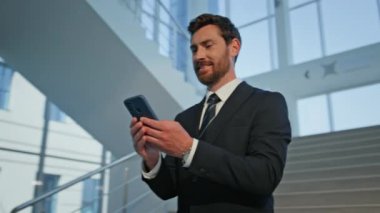 Modern ofis binasının merdivenlerinde gülümseyen bir çalışan akıllı telefon görüyor. Takım elbiseli, kendine güvenen bir yönetici cep telefonuyla çevrimiçi iletişimden hoşlanır. Şirket yöneticisi cep telefonu içeriğine göz atıyor.
