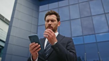 Sinirli CEO ofis binasının yakınındaki akıllı telefonu kontrol ediyor. Telefon mesajı okuyan stresli işadamı şehir manzarasında kötü haberlerden endişeleniyor. Memnun olmayan işletme müdürü cep telefonunu dışarıda arıyor..