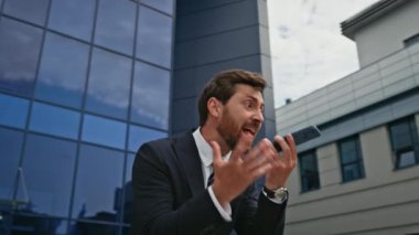 Stresli girişimci cep telefonuyla bağırıyor. Şehir sokağını kapatıyor. Kızgın iş adamı modern ofis binasının dışında akıllı telefonla tartışıyor. Öfkeli patron bağırıyor, bitiriyor, duygusal olarak arıyor.