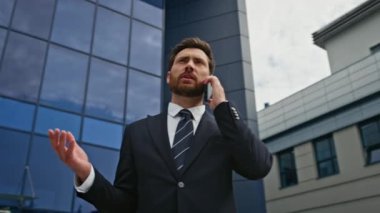 Modern ofis binasının önünde cep telefonundan konuşan sakallı işadamı. Şehir sokağında ciddi bir yönetici iş görüşmesi yapıyor. Güvenilir CEO akıllı telefondan iş konuşmasına girdi