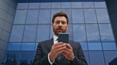 Ofis binasının dışındaki akıllı telefon mesajlarına göz atmak tatmin edici. Başarılı bir iş adamı caddede cep telefonuna bakıyor. Gülümseyen menajer evet diyor..