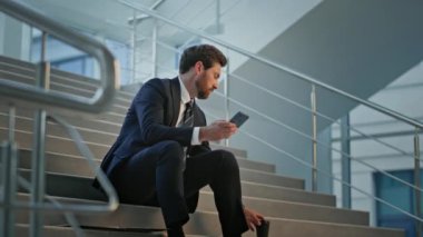 Profesyonel girişimci merdivenlerde oturuyor modern ofis elinde kahve tutan akıllı telefonu kontrol ediyor. Sakallı erkek yönetici, şirkette içki molası verirken cep telefonuna bakıyor. Çalışan dinleniyor