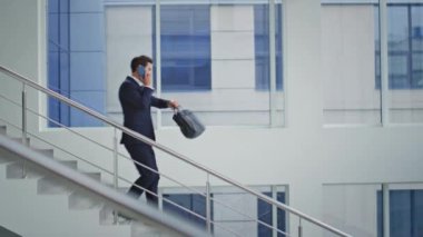 Ofis merdivenlerinden inen bir adam cep telefonuyla konuşuyor. Kol saatini kontrol ediyor. Kendine güveni tam bir işadamı merdivenlerden aşağı yürüyor modern bir binada evrak çantası taşıyor. Yönetici akıllı telefonu arıyor, aşağı iniyor..