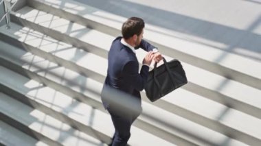 Acele eden işadamı, kol saatini kontrol ediyor, merdivenleri tırmanıyor, parlak ofis binası. Üst kata siyah deri çanta taşımakla meşgul bir yönetici. Sakallı girişimci üst kata şık bir takım elbiseyle çıkıyor..