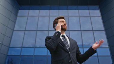 İş adamı ofis binasının dışında cep telefonuyla görüşüyor. Şehir cam mimarisine karşı yapılan konuşmada başarılı bir yönetici. Gülümseyen patron akıllı telefon sohbetinin tadını çıkarıyor..