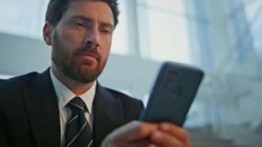 Akıllı telefonu kullanan odaklanmış bir işadamı merdivenlerde oturup yakın plan kahve içiyor. Sakallı yönetici merdivenlerde telefonu kontrol ediyor. Ciddi adam cep telefonu mesajını okuyor. İçkisini yudumluyor..