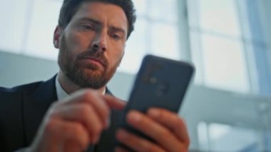 İş adamının elleri hafif bina iç çekiminde akıllı telefonu kaydırıyor. Takım elbiseli ciddi bir yönetici, modern ofiste cep telefonu e-postalarına bakıyor. Cep telefonuyla bilgi analiz eden düşünceli bir adam.