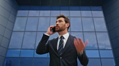 Mad CEO 'su cep telefonunda bağırıyor. Cam ofis dışında duygusal hareketler yapıyor. Akıllı telefondan bağıran öfkeli bir yönetici sokakta stres hissediyor. Kızgın işadamı modern binanın yakınında tartışıyor..