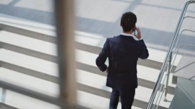 Modern ofis binasının merdivenlerinde yürüyen yöneticiyi arıyorum. Başarılı bir girişimci cep telefonu konuşmalarında merdivenlere tırmanarak iş anlaşmasını tartışıyor. Zarif sakallı patron akıllı telefondan yukarı çıkıyor..