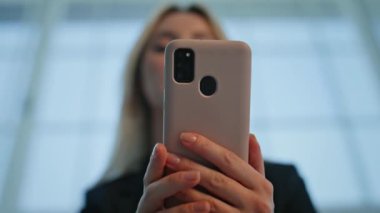 Akıllı telefon mesajını okuyan mutlu girişimci aydınlık bina yakınlaşmasında sevinçle kazanıyor. Modern ofis içinde gülümseyen iş kadını cep telefonuna göz atıyor. Kapalı alanda cep telefonu izleyen pozitif kadın..