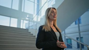 Kapalı kapılar ardında kamerada gülümseyen kadın yönetici. Ofis merdivenlerinde şık bir takım elbise giymiş kendine güvenen bir iş kadını. Başarılı liderlik gösteren pozitif kadın.