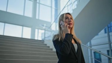 Şirketin ofisindeki sarışın müdür cep telefonuyla konuşuyor. Gülümseyen iş kadını merdivenlerde akıllı telefonu arıyor. Zarif kadın CEO merdivenlerde dostça cep telefonu sohbetinin tadını çıkarıyor..