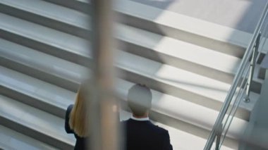 Modern ofis binasında yürüyen iki profesyonel. Gülümseyen şirket arkadaşları kahve siparişiyle merdivenleri tırmanmaktan bahsediyorlar. İş adamları molada içki içmeyi tartışıyor..