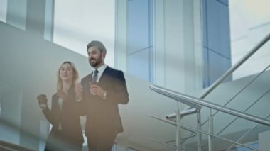 Gülümseyen iş arkadaşları aşağıda arkadaşça sohbetin tadını çıkarıyorlar. Pozitif iş kadını merdivenlerden inip kahve içiyor. Rahat iş ortakları ofiste birlikte konuşuyorlar..