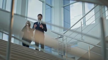 İş adamları ellerinde kahve fincanlarıyla aşağıya iniyor. Gülümseyen iş kadını içki molası veriyor. Mutlu ortaklar resmi olmayan bir ortamda projeyi tartışıyor..