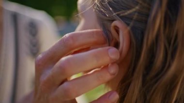 Anne eli kızının saçına dokunuyor. Çimlere yakın yerde sevgi gösteriyor. Yaz pikniğinde güzel sarışın kızı okşayan tanınmamış bir anne. Çocuğuyla gün ışığında iletişim kuran kadın ebeveyn