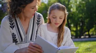 Mutlu aile kitap okuma toplantıları. Samimi bahçede yakın çekim. Güzel bir kadın ve çocuk yeşil çimlerde dinleniyor peri masalının tadını çıkarıyorlar. Önemseyen kadın ve çocuk, yaz tatilini birlikte geçiriyorlar. 