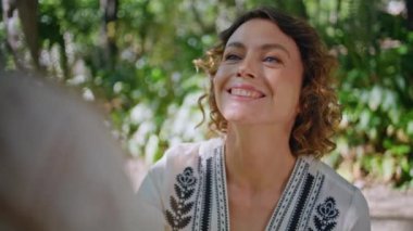 Portre mutlu anne konuşuyor çocuk gün ışığında yürüyor güzel yayılmış park. Kıvırcık annenin güneşli yeşil bahçede küçük kızıyla konuştuğu yakın plan. Hafta sonu kucaklaşan sevimli bir aile. 