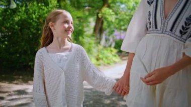 Kimliği belirsiz bir kadın, küçük bir çocuğu güzel yeşil bir parkta el ele gezdiriyor. Gülümseyen küçük kız anne görünümlü aile hafta sonunun tadını çıkarıyor. Anne koluyla gezen sevimli bir çocuk. Boş zaman konsepti 