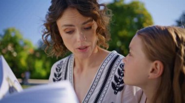 Anne çocuğu kitap topluyor, bahçeye yakın bir yerde. Güzel kadın ve kız yeşil çimlerde dinleniyor peri masalının tadını çıkarıyorlar. Önemseyen kadın ve çocuk yaz tatilini güneşli parkta birlikte geçiriyorlar.