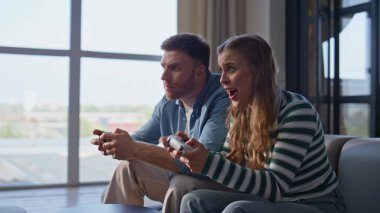 Oyuncuların eşleri birlikte rahat koltukta oturup bilgisayar oyunu oynarlar. Hayal kırıklığına uğramış bir çift üzgün hissederek oyunu kaybediyor. Modern çiftler dairelerinde online yarışma konsolları bulundurmaktan hoşlanıyorlar