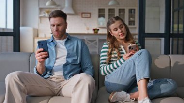 Yumuşak koltukta oturan akıllı telefonları kullanan iki kişi. Cep telefonlarını daktilo eden evli çift evde sıkılıyor. Cep telefonlu ruh eşleri başlarını çeviriyor. Birbirlerine gülümsüyorlar. 