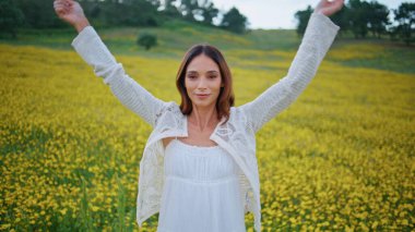 Kırsal kesimde yaşayan bir kız sarı çayırda yaban çiçeğini kollarında tutuyor. Çiçek taşıyan mutlu gülümseyen kadının portresi yaz doğasında el kaldırıyor. Romantik kadın çiçekli tarlada tek başına yürüyor. 