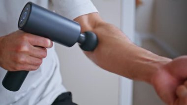 Apartman dairesinde kol üstüne kol masajı. Kas ağrısını evde dindirmek için elektronik masaj aleti kullanan tanınmayan bir sporcu. Antrenmandan sonra bilinmeyen bir sporcunun vücudu iyileşiyor..