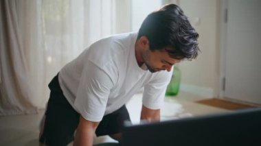 Profesyonel eğitmen çevrimiçi apartman katında diz çökmüş. Spor egzersizlerini açıklayan video dersi veren odaklanmış İspanyol adam. Motivasyonlu adam koçu sakin bir evde çalışıyor.