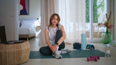 Rahatlamış kadın yoga minderinin etrafında spor aletleri vardı. Spor giyimli genç, sıska bir bayan spor salonunda poz veriyor. Çekici bayan sporcu sabah antrenmanından sonra dinleniyor..