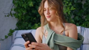 Yeşil bahçe terasında oturan hoşnutsuz bir kadın cep telefonuna bakıyor. Kaşları çatık bayan, kafası karışmış akıllı telefon mesajı okuyor. Açık verandada cep telefonuyla haberlere odaklanmış bir kız..