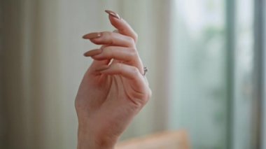 Nişan yüzüğüyle kadın eli havada el hareketi yapıyor. Şık manikürlü kadın parmakları elmas taşlı güzel altın düğün mücevherleri takıyor. Meçhul zarif bir kız Nazik bir kol düşünüyor.