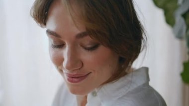 Evde gülümseyen sakin bir kadının portresi. Rahat bayan kameraya bakıyor. Sabah ışığı altında kendini huzurlu hissediyor. Doğal güzellikte güzel bir kız. Oturduğu dairede sakin bir hafta sonunun tadını çıkarıyor..