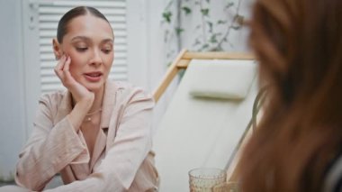 Kaygısız esmer, terasta arkadaşça buluşmanın keyfini çıkar. Gülümseyen bayan kafe terasında hoş sohbetler yapar. Mutlu kadın gülüyor bilinmeyen kız arkadaşıyla şakalaşıyor.