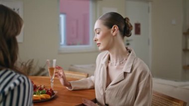 Zarif bayan, evde meyve ve içeceklerle dostça buluşmaktan zevk alır. Şarap kadehi tutan gülümseyen kadın, konuşan bayan arkadaş. Mutlu kız, mutlu aile toplantılarında kız arkadaşıyla haberleri paylaşıyor.