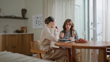 Mutfak masasında moda tarzı dergileri tartışan iki bayan. Rahatlamış kadınlar sohbet etmekten zevk alıyorlar. Mutlu bayan arkadaşlar, dostça bir evde meyve ve içecek yiyorlar..