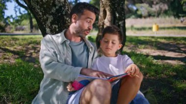 Orman yakınlarında yeşil çimlerde oturan sevimli bir aile kitabı okuyor. Sevimli küçük çocuk büyük bir ağacın altında babasıyla geçirdiği hafta sonu mutluluğunu ifade ederken eğleniyor. Sevgi dolu ebeveyn oğul ilişkileri 