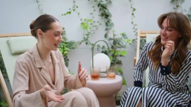 Neşeli bayanlar haberleri tartışıyor ve çağdaş teraslarda canlı canlı konuşuyorlar. İki gülen arkadaş terasta neşeli bir sohbete girişiyor. Mutlu kadınlar duygusal olarak tanışmaktan zevk alırlar..