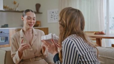 Kız, doğum günü kutlamasında arkadaşına hediye veriyor. Duygusal bir kadın kanepede oturan sevgilisinden hediye paketi alıyor. Mutlu bayanlar hediye verme ve kaynaşma anının tadını çıkarıyorlar..