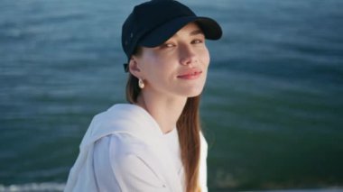 Rıhtımda oturan kadın turist güzel yaz gününün tadını çıkarıyor. Deniz dalgalarının yanında gülümseyen, esmer, çekici bir kadın portresi. Kaygısız kız mavi okyanus suyunda poz veriyor.