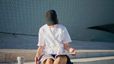 Moda dergisi okuyan bir kadın yaz günü şehir merdivenlerinde oturuyor. Siyah şapkalı rahat bayan sayfaları çeviriyor moda dergisi sokaklarda rahatlıyor. Güneşli meydanda genç esmer görünümlü makaleler.