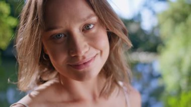 Parkta gülümseyen bir kamera var. Ormanın yeşillik portresiyle çevrili güzel bir kadın. Mutlu kız anın tadını çıkarıyor huzur ve mutluluk güneşli bir günde seviniyor.