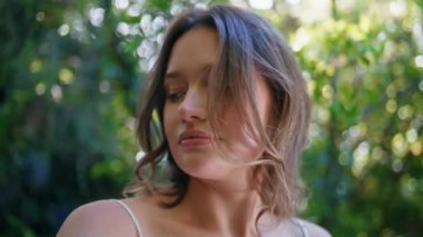 Romantik model doğanın yeşillik ağacına yakın durmasını sağlıyor. Güneş ışığı portresinde güzel bir kadın saçlarına dokunuyor. Rahat bayan yemyeşil ormanlarda hafif esintinin tadını çıkarıyor.