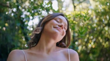 Yakın çekim şehvetli kadın, hafif rüzgârlı ormanın tadını çıkarıyor. Portre. Nazik model. Huzurlu, doğal çevrenin değerini bilen. Ormanlara dalmış rahat genç bayan doğa güzelliği 