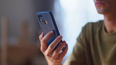 Adamın elleri cep telefonunu tutuyor. Kapalı çekimde dinleniyor. Bilinmeyen zeki serbest çalışan dairedeki cep telefonundan sosyal medyayı izliyor. İşten sonra akıllı telefondan mesaj okuyan tanınmayan bir adam.