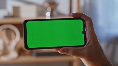 İş adamı yeşil ekran akıllı telefonuyla iş yerinde video görüşmesi yapıyor. Tanımlanamayan yönetici cep telefonunda iş mesajı açıyor. Erkek serbest çalışan parmak kroma tuşlu telefona dokunuyor