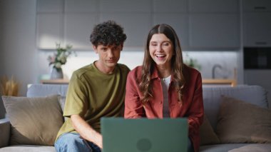 Gülümseyen çift, oturma odasını kapatıyor. Mutlu ruh eşleri diz üstü bilgisayara el sallıyor rahat koltukta dinleniyorlar. Olumlu evli çiftler evlerinde dostça buluşmanın keyfini çıkarırlar.