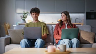 Dizüstü bilgisayarlar üzerinde çalışan serbest çalışanlar birlikte kanepede oturuyor. Odaklanmış koca karısı uzaktan bilgisayarda yazı yazıyor. Oturma odasında birbirlerini izliyorlar. Konforlu dairede görevleri çözen iki kişi. 