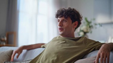 Modern oturma odasında kanepede oturup televizyon izleyen rahat bir adam. Tek başına televizyon izleyen pozitif bir adam evde günlük haberlerin tadını çıkarıyor. Genç hippi kendini mutlu hissediyor. Apartman dairesinde dinleniyor. 