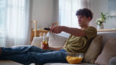 Sıkıcı adam TV 'de uzaktan kumandayla kanalı değiştiriyor. Dinlenen adam en sevdiği televizyon programını buldu. Rahatlamış, neşeli hipster evde takılıyor, abur cuburla bira içiyor. 